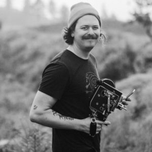 black and white portrait of photographer Dylan M Howell holding a vintage camera