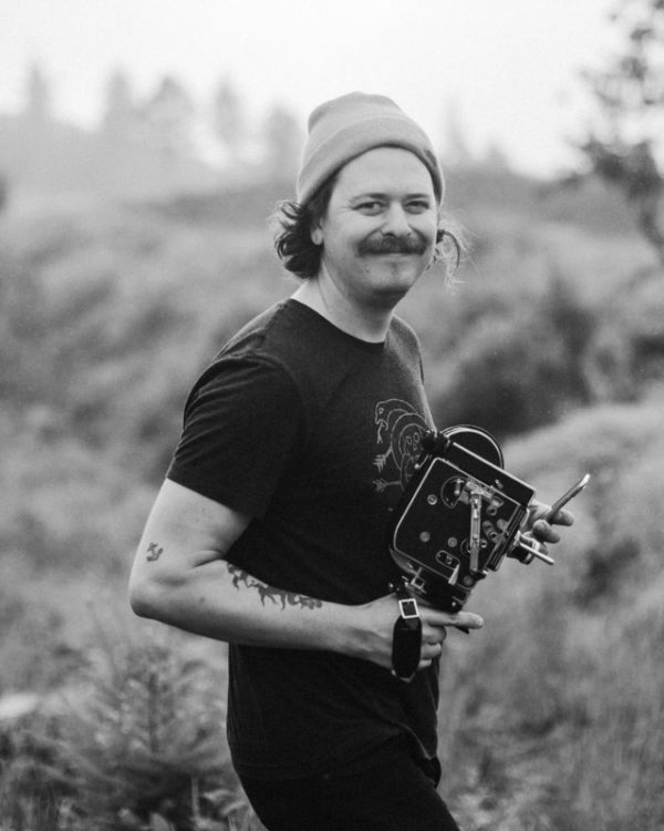 black and white portrait of photographer Dylan M Howell holding a vintage camera